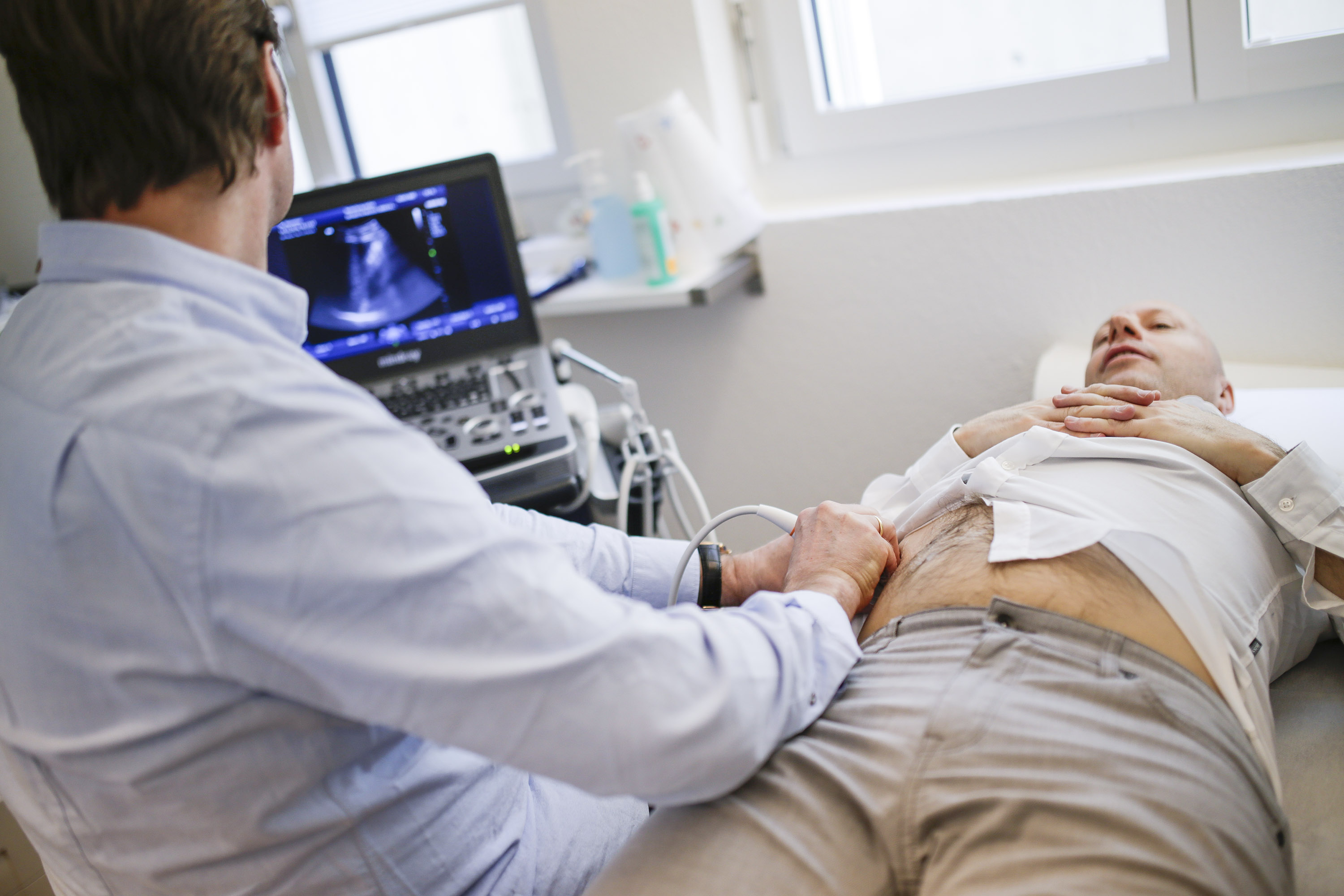 Dr. Marcus Hassemer von Hausarzt Volketswil untersucht einen Patienten mit Ultraschall.